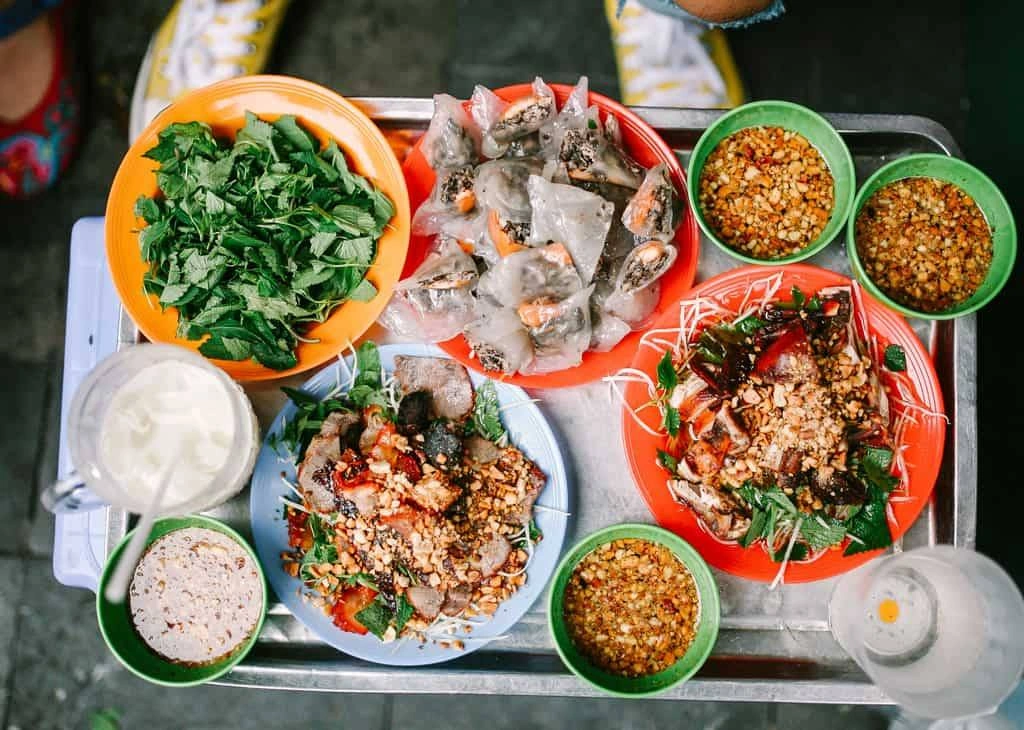 Street food vendors and diners sitting on small stools in Hanoi Old Quarter.