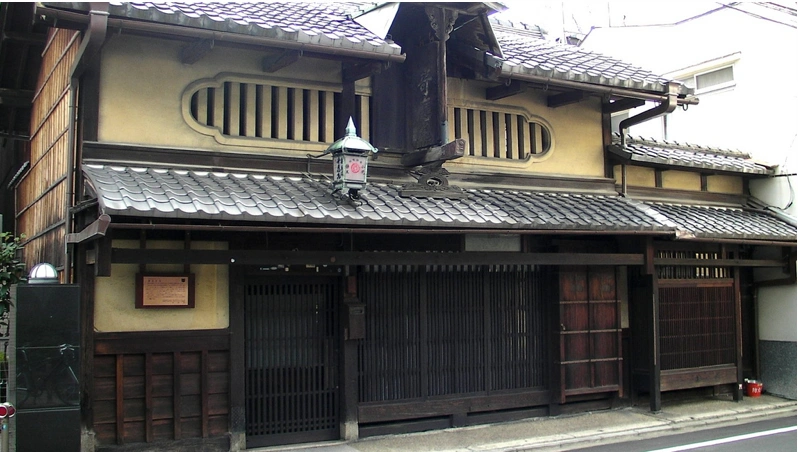 Traditional machiya townhouses on a quiet Kyoto street with wooden facades and noren curtains.