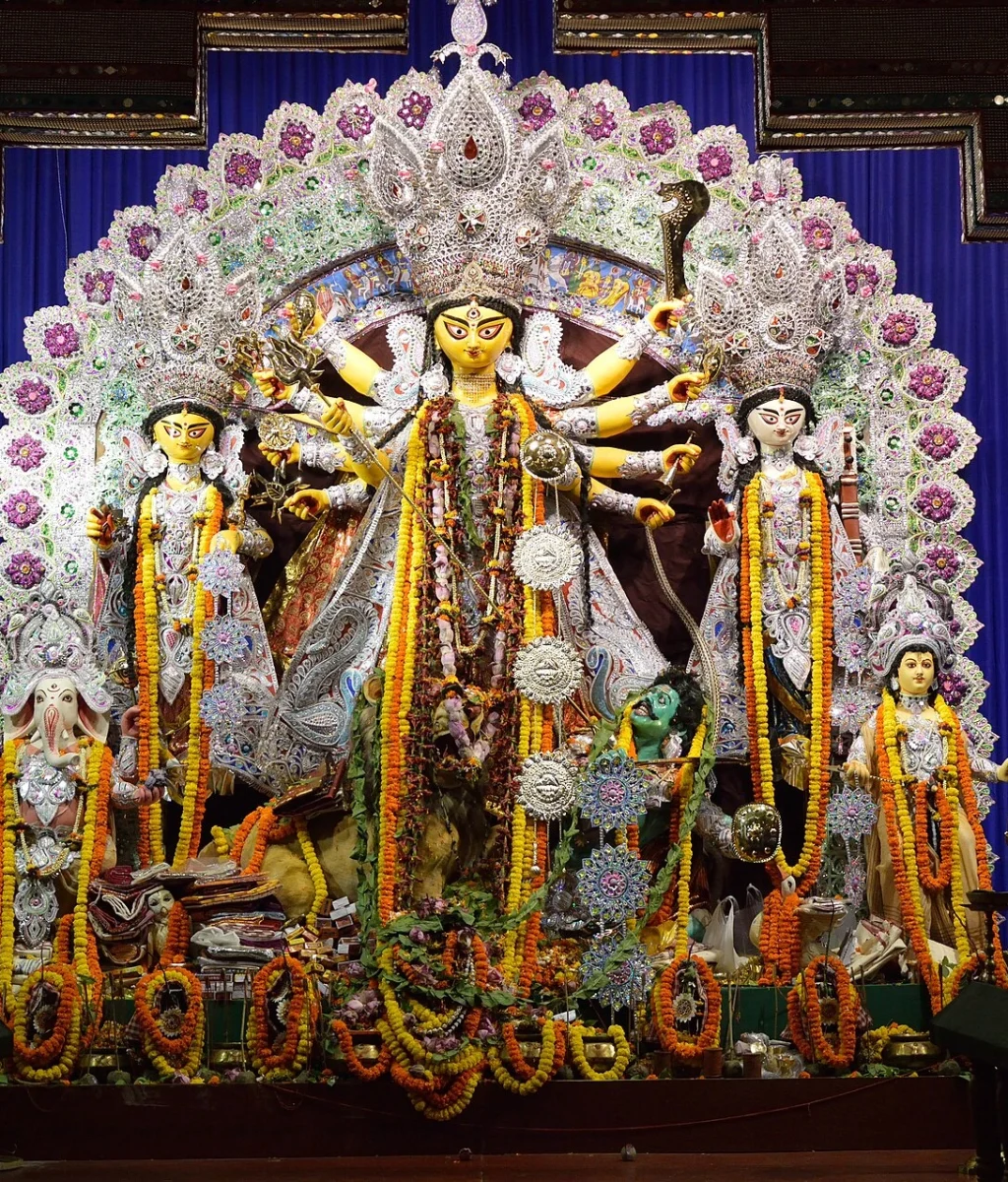 Durga Puja pandal in Kolkata showing public art, lights, and festival crowd movement.