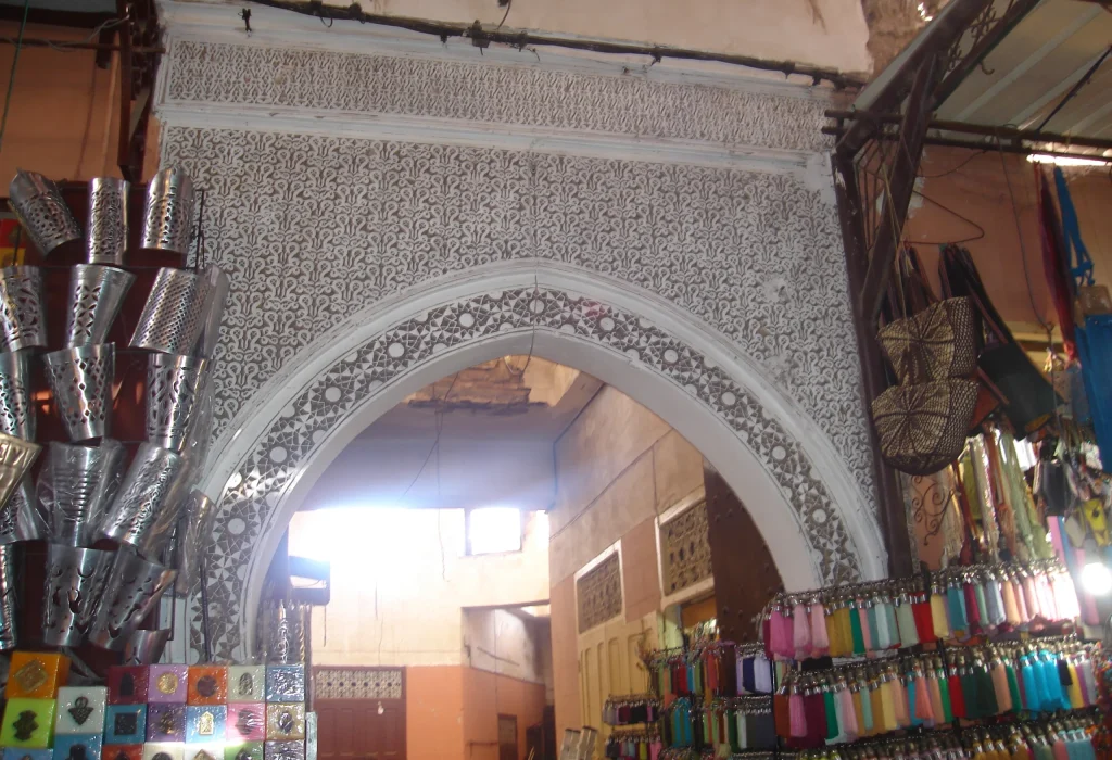 Souk in Marrakech with Moroccan lamps, textiles, spices, leather goods, and market lanes.